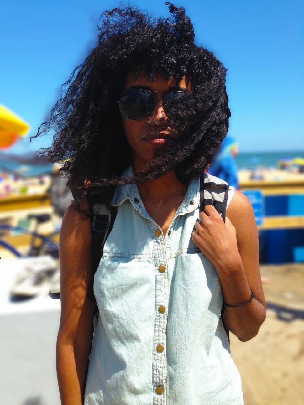 Free Image of Woman Standing on Beach With Wind-Blown Hair 