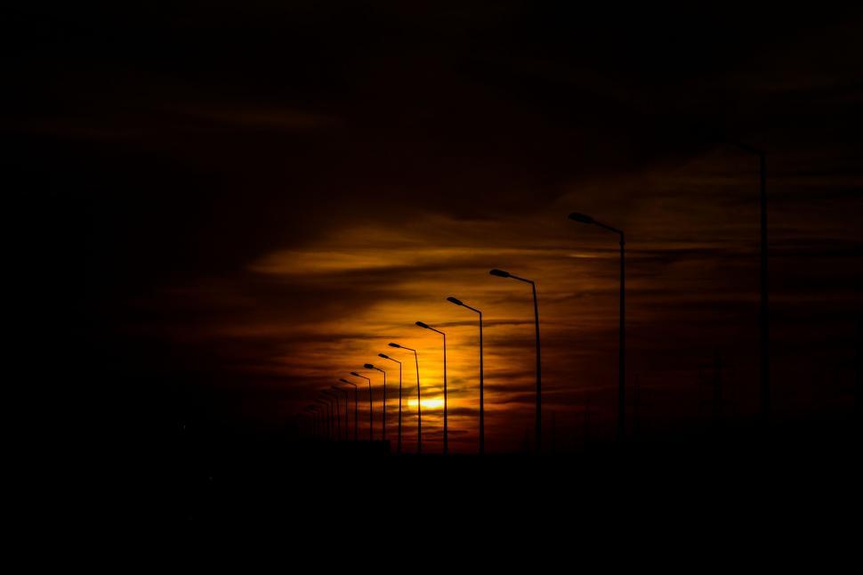 Free Image of Sun Setting Behind Row of Street Lights 