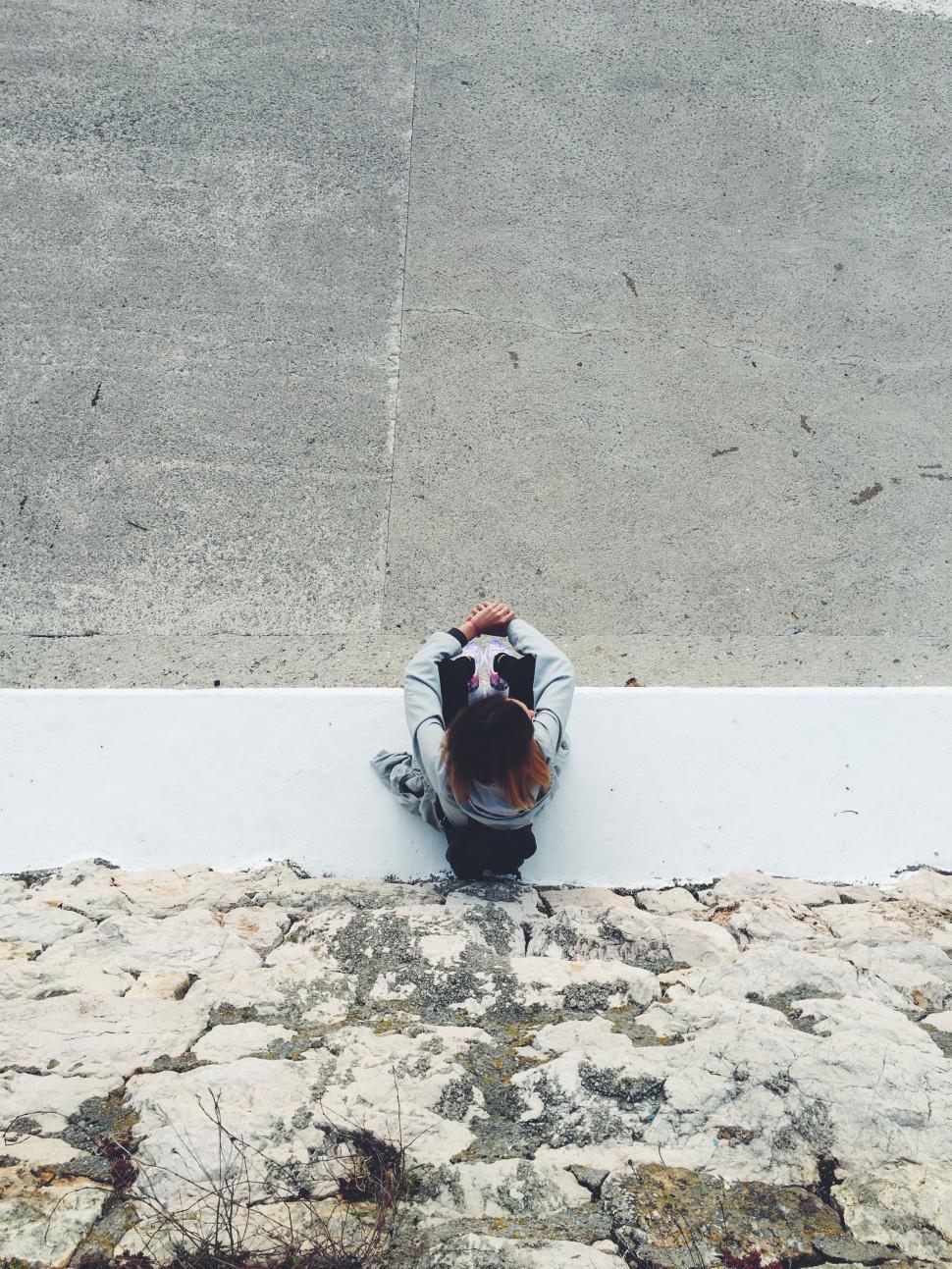 Free Image of Person Sitting on Ledge Looking Down 