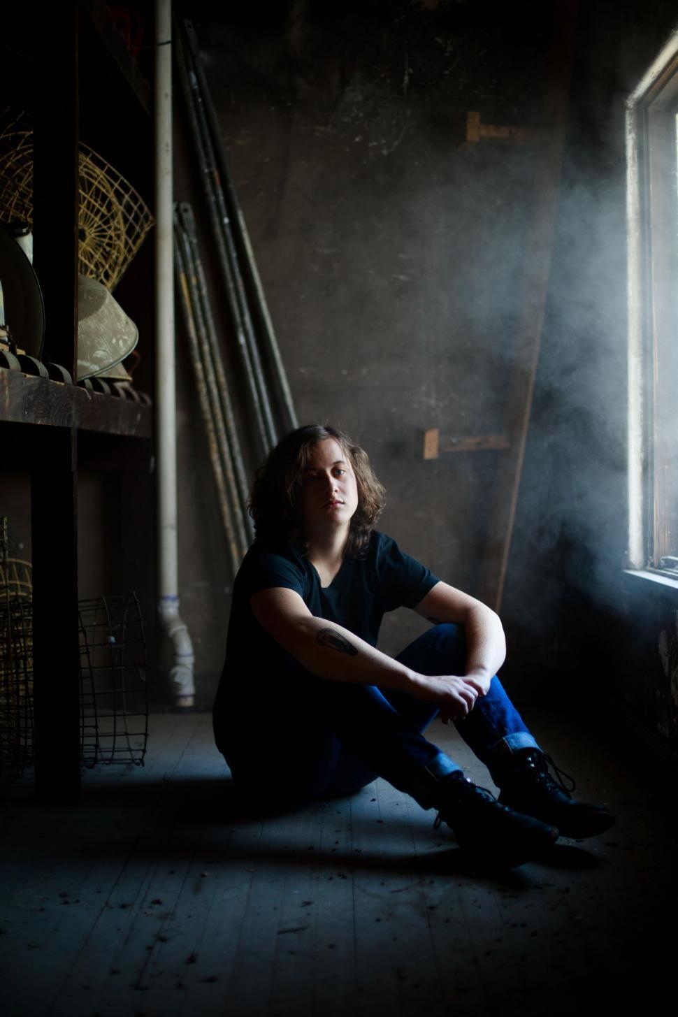 Free Image of Woman Sitting on Floor in Front of Window 