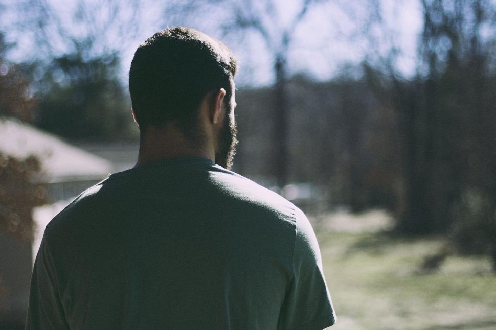 Free Image of Man Holding Frisbee Standing in Front of Tree 