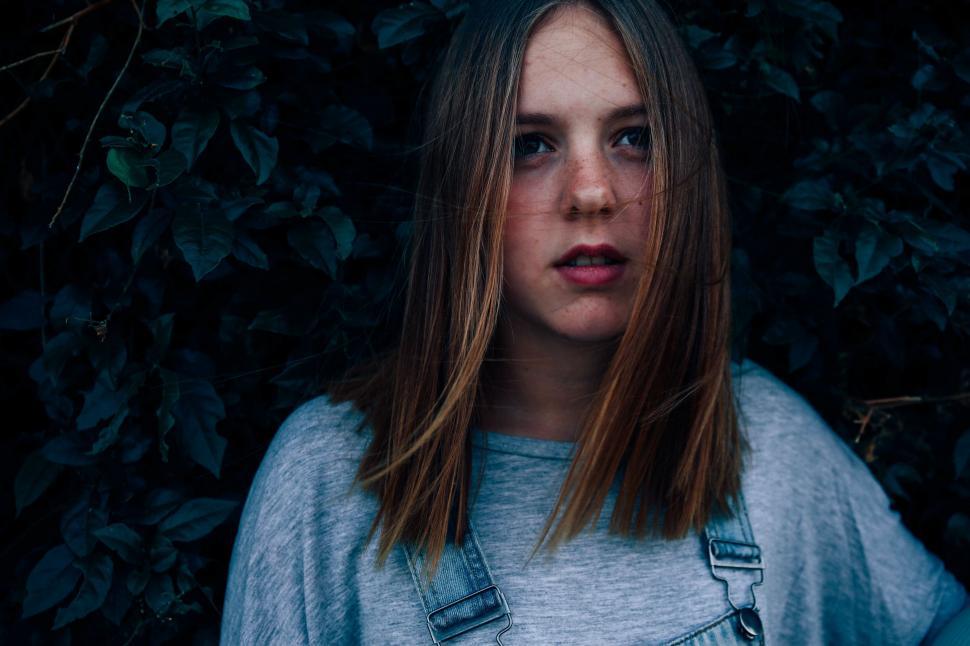 Free Image of Woman With Long Hair Standing in Front of Bush 