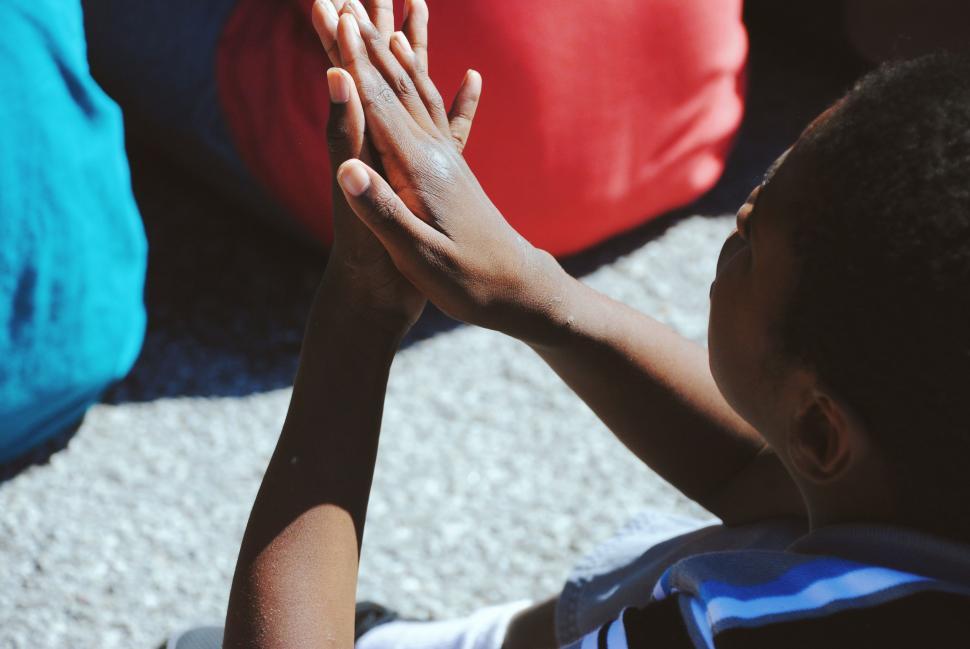 Free Image of Young Boy Sitting on Ground Holding Hands Together 