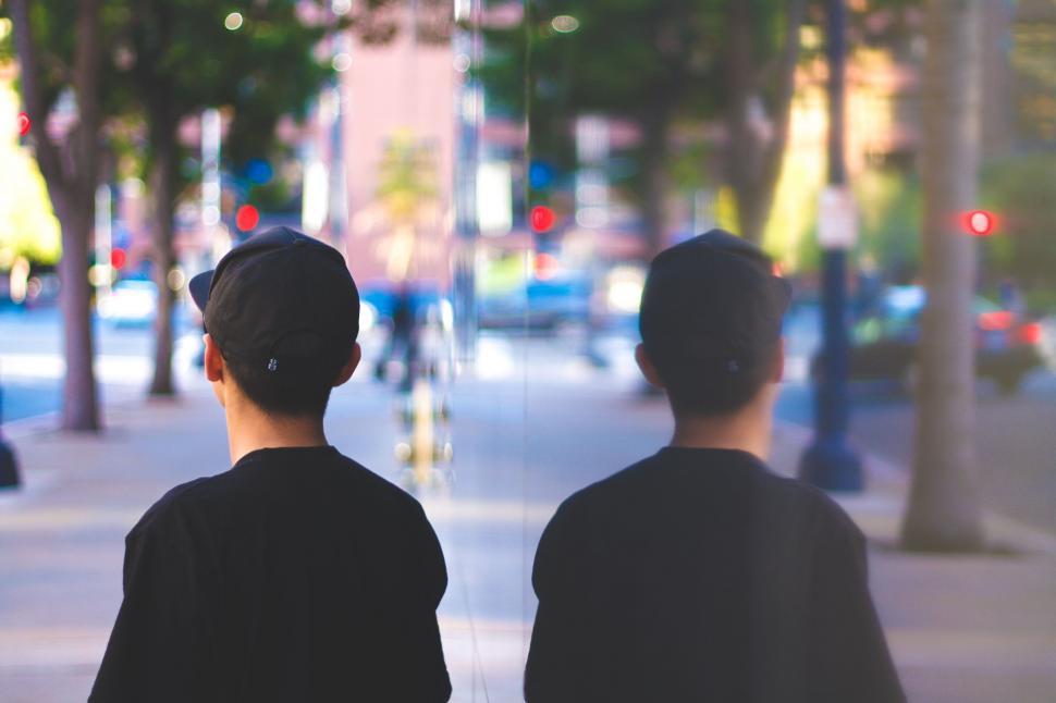 Free Image of A man and his reflection along a city street 
