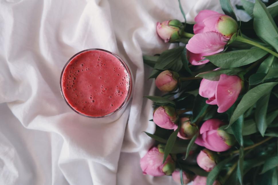 Free Image of Red Liquid in Glass Beside Pink Flowers 