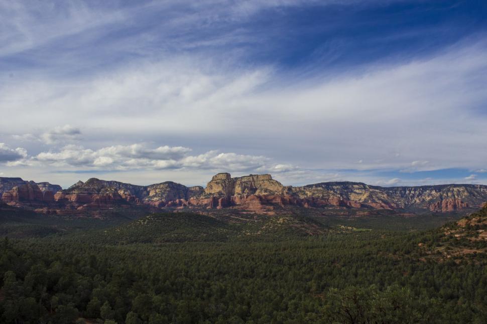 Free Image of Majestic Mountains and Trees Beneath Cloudy Sky 