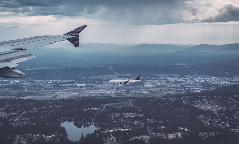 Free Image of Airplane Flying Over City Under Cloudy Sky 