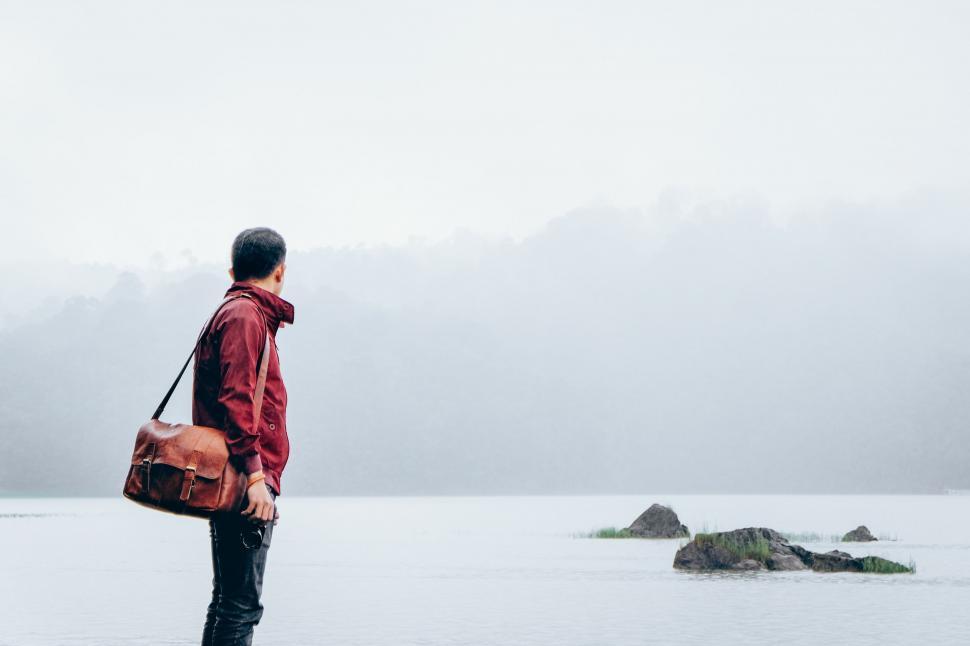 Free Image of Man Standing in Snow With Red Bag 