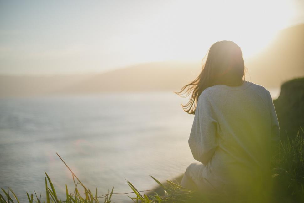 Free Image of Woman Sitting on Grass by Water 
