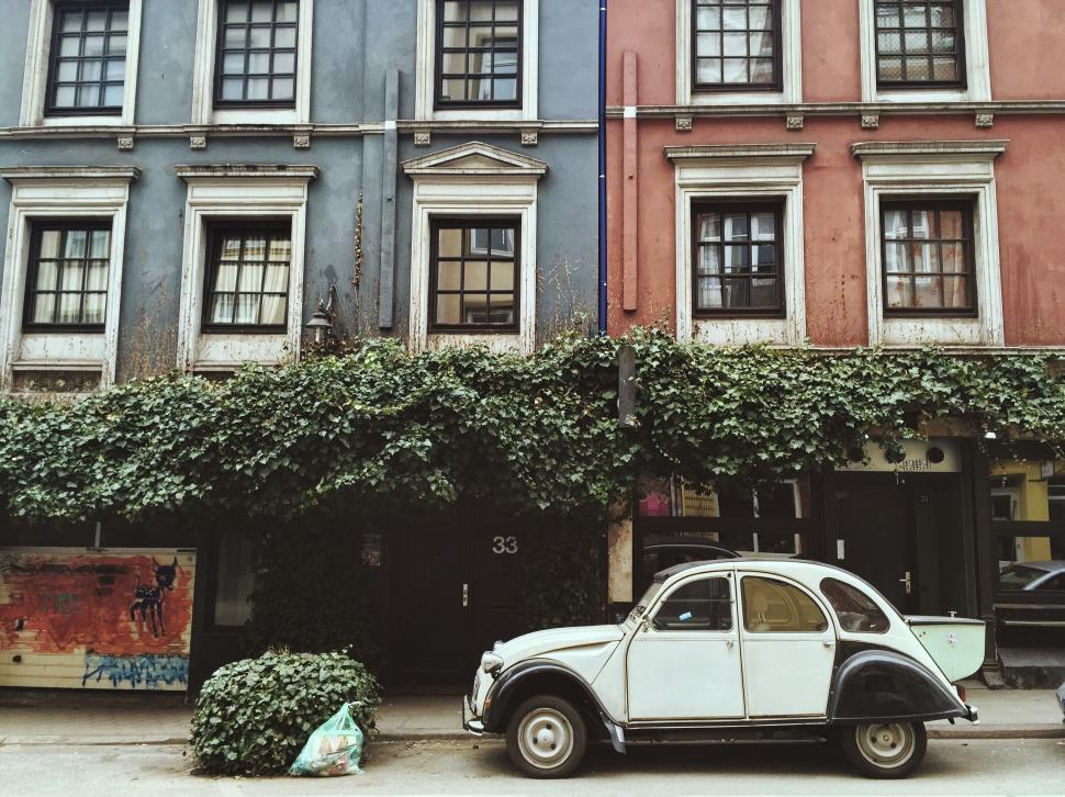 Free Image of Car Parked in Front of Building Covered in Ivy 
