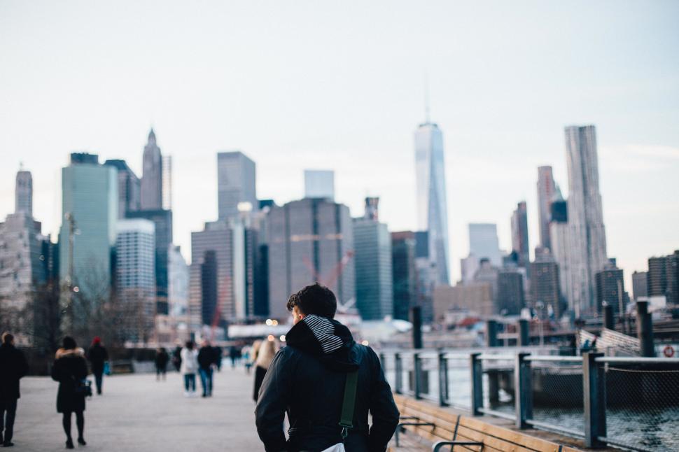 Free Image of Man Walking Down Sidewalk Next to Water 