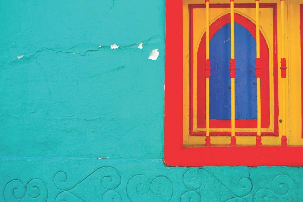 Free Image of Blue and Yellow Building With a Red Window 