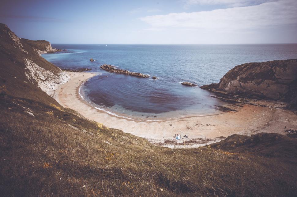 Free Image of A View of a Sandy Beach With a Body of Water 