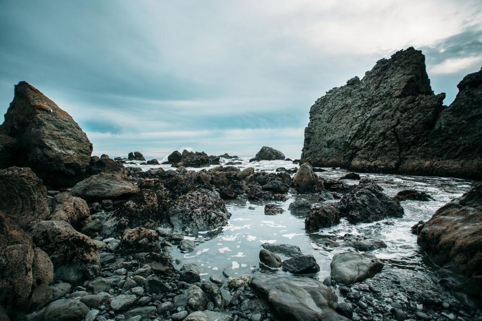 Free Image of Rocky Beach With Water Body Surrounded by Rocks 