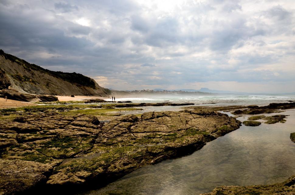 Free Image of Person Standing on Rocky Beach Next to Ocean 