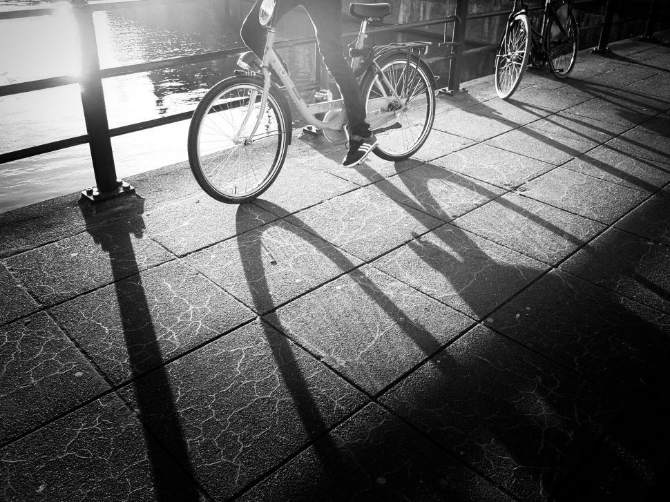 Free Image of Man Riding Bike Along Sidewalk by Water 