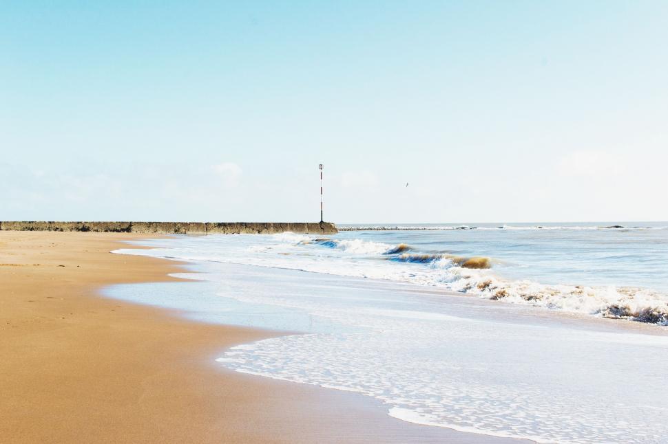 Free Image of Sandy Beach Alongside Ocean Under Blue Sky 