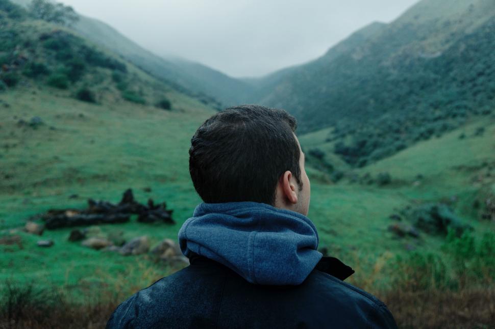 Free Image of Man Standing in Front of Lush Green Hillside 