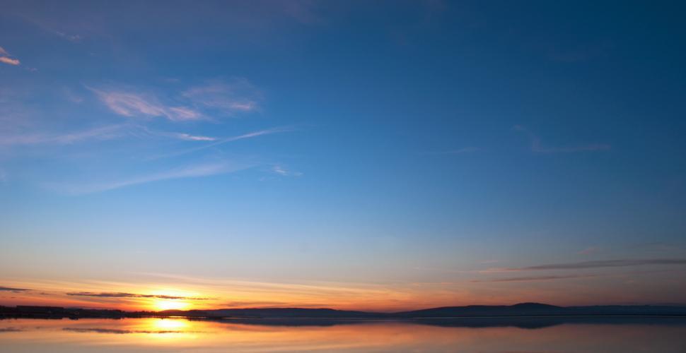 Free Image of The Sun Sets Over a Body of Water 