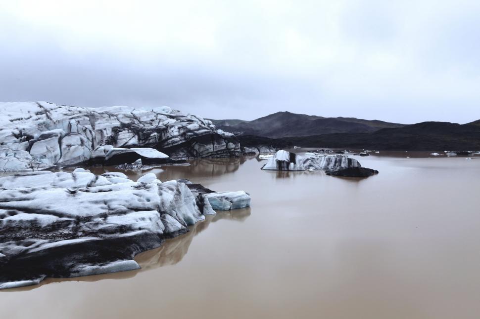Free Image of Snow Covered Rocks Surrounding Large Body of Water 