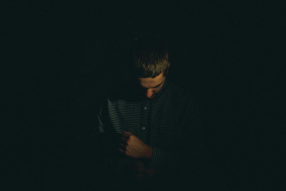 Free Image of Man Standing in the Dark Reading a Book 