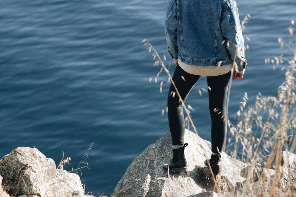 Free Image of Woman Standing on Rock by Water 