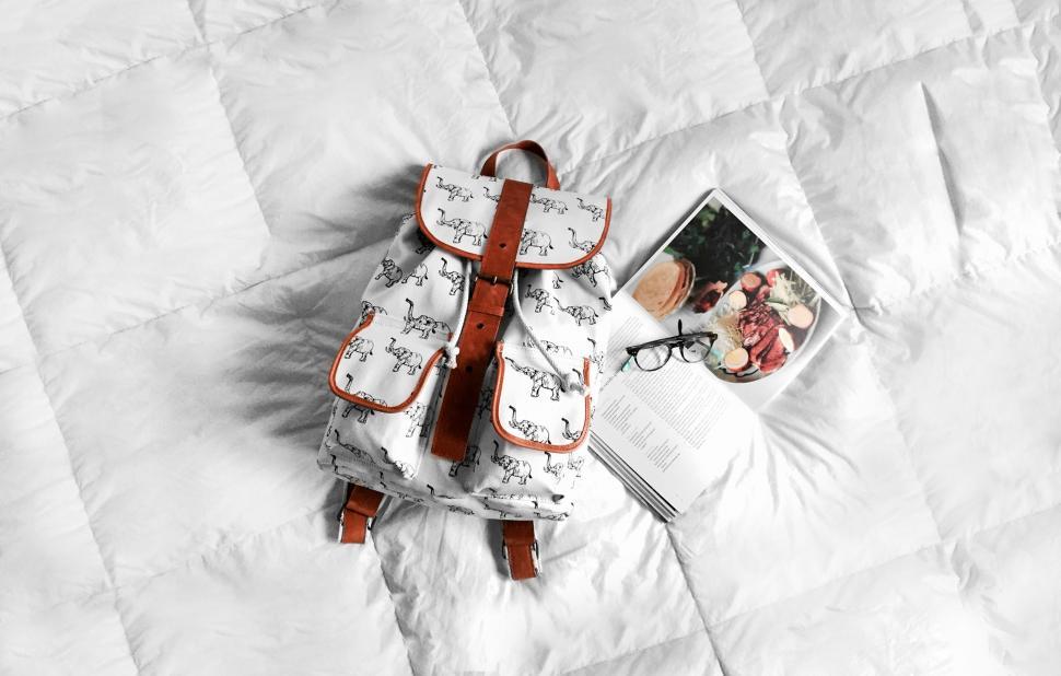 Free Image of Backpack on Bed Next to Book 