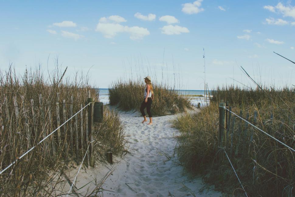 Free Image of Man Walking Down Path to Beach 