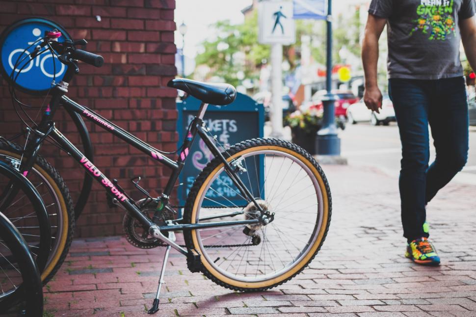 Free Image of Man Walking Down Sidewalk Next to Bike 