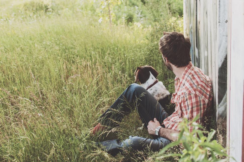 Free Image of Man Sitting in Field With Dog 