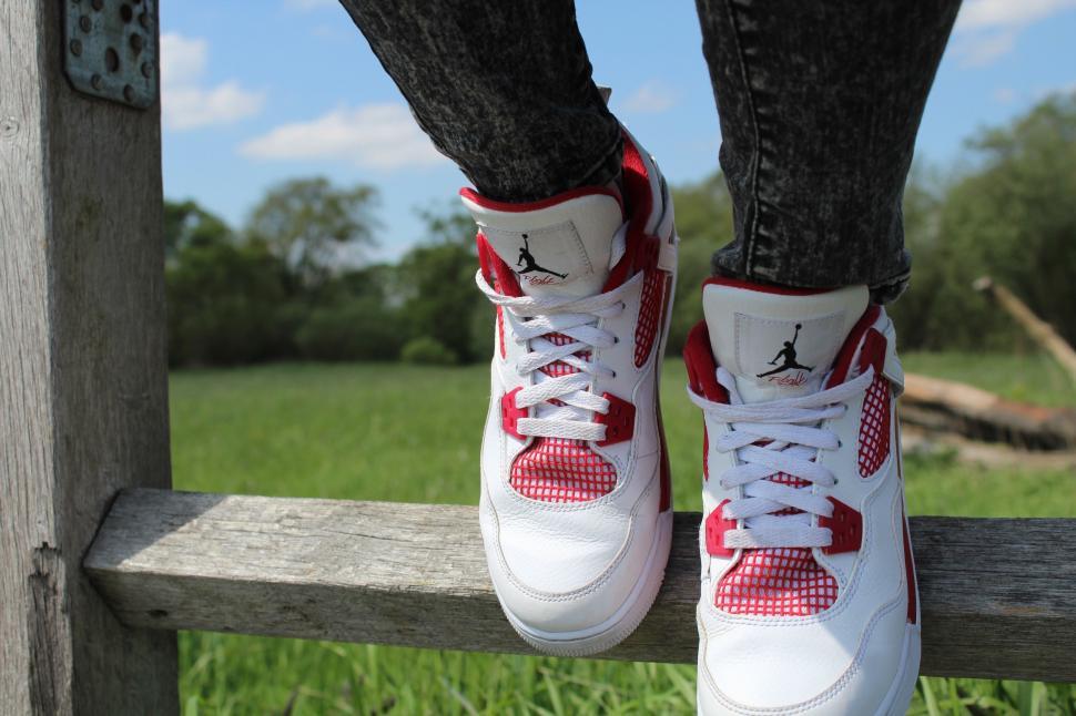 Free Image of Person Standing on Wooden Fence in White and Red Sneakers 