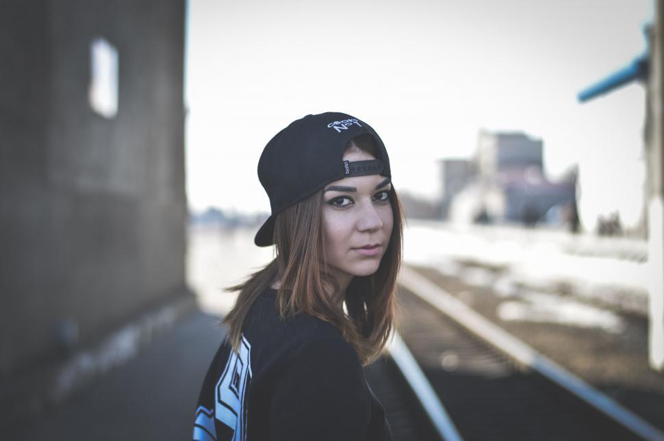 Free Image of Woman Wearing Hat Standing in Front of Train Track 