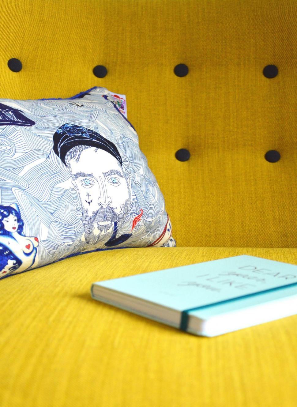 Free Image of Yellow Couch With Book and Pillow 