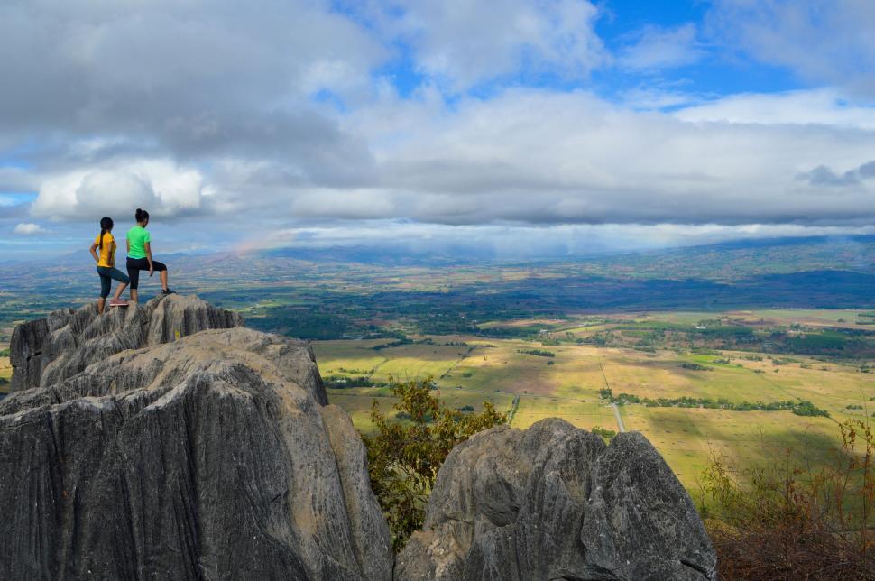 Free Image of Two People Standing on Top of a Large Rock 