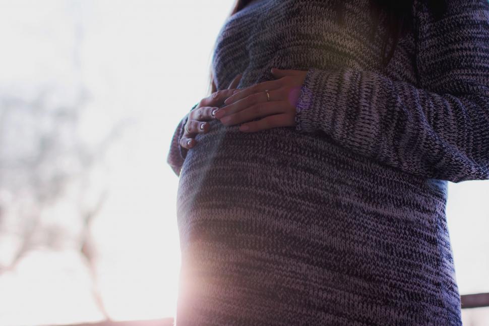 Free Image of Pregnant Woman Holding Her Stomach by Window 