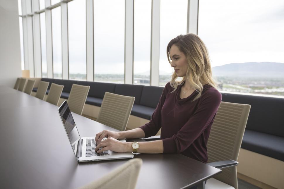 Free Image of Woman Sitting at Table Using Laptop Computer 