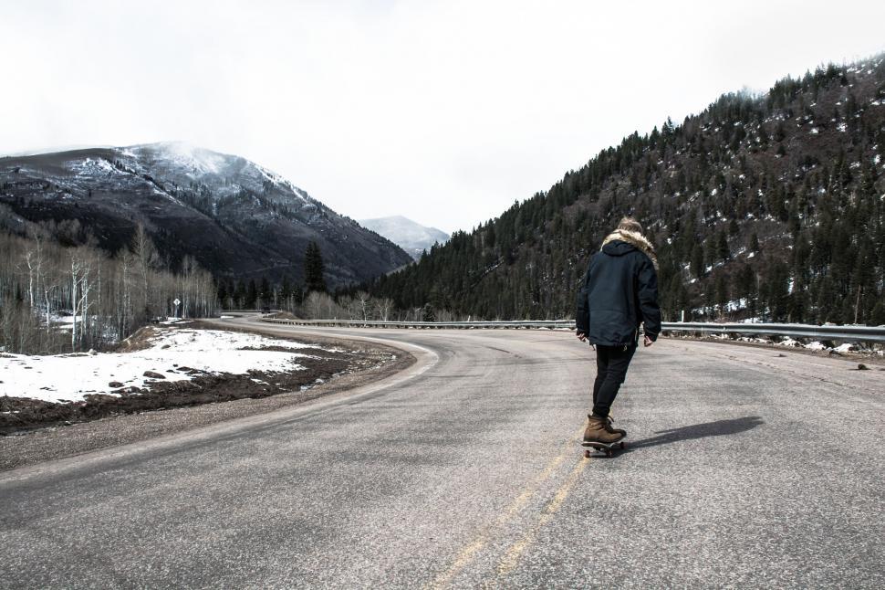 Free Image of Man Riding a Skateboard Down a Road 