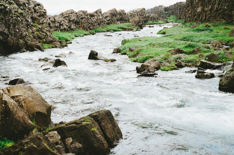 Free Image of River Running Through Lush Green Rocky Hillside 