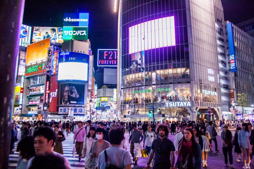 Free Image of Crowd of People Walking Across Street Next to Tall Buildings 