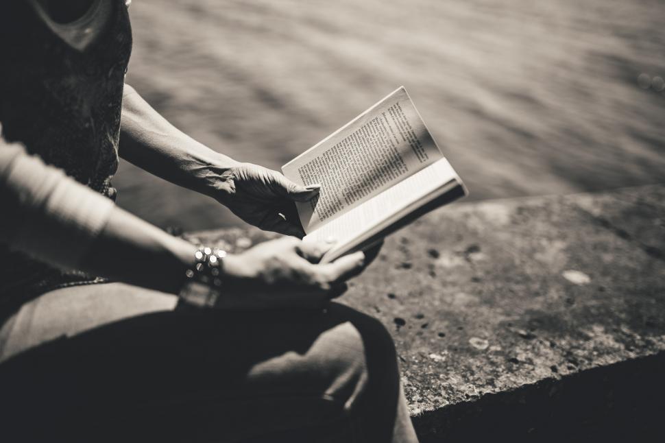 Free Image of Woman Reading Book While Sitting on Ledge 