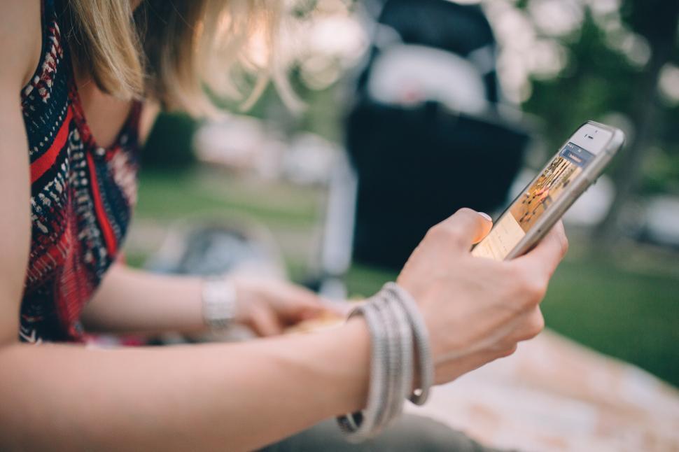 Free Image of Woman Sitting on Bench Using Cell Phone 