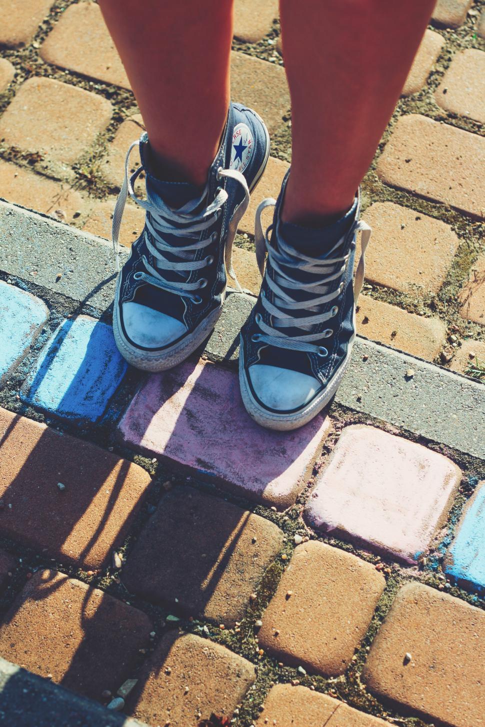 Free Image of Person Crossing Legs on Sidewalk 