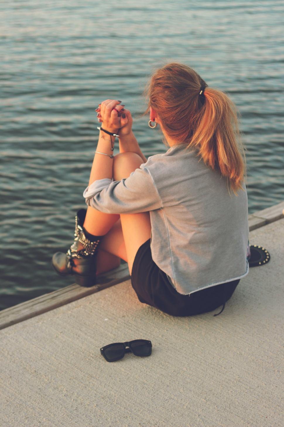 Free Image of Woman Sitting on Edge of Pier by Water 