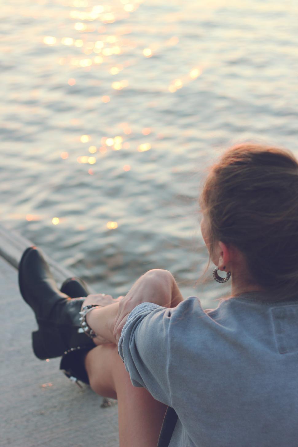 Free Image of Woman Sitting on Edge of Boat Looking at Water 