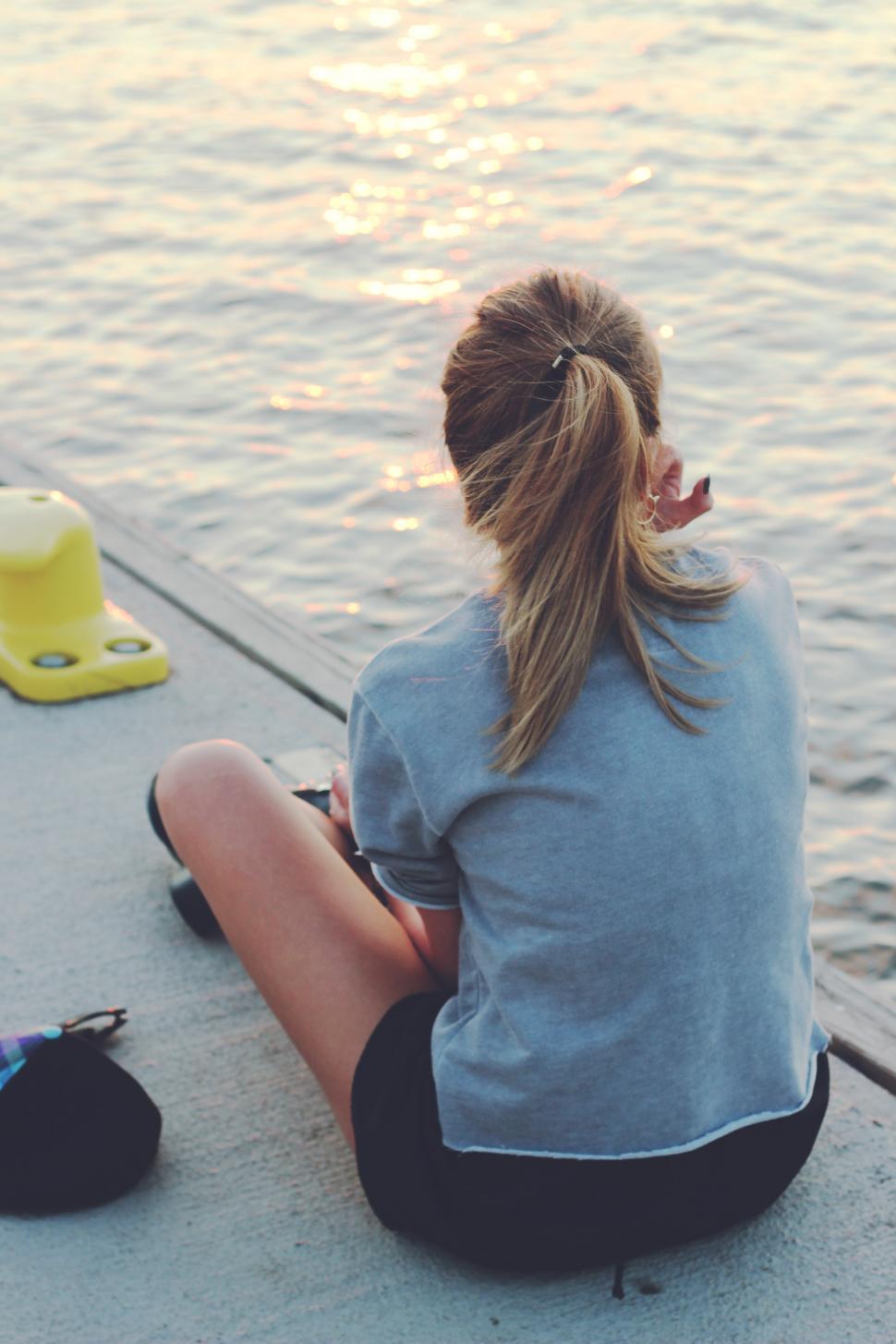 Free Image of Woman Sitting on Dock by Water 