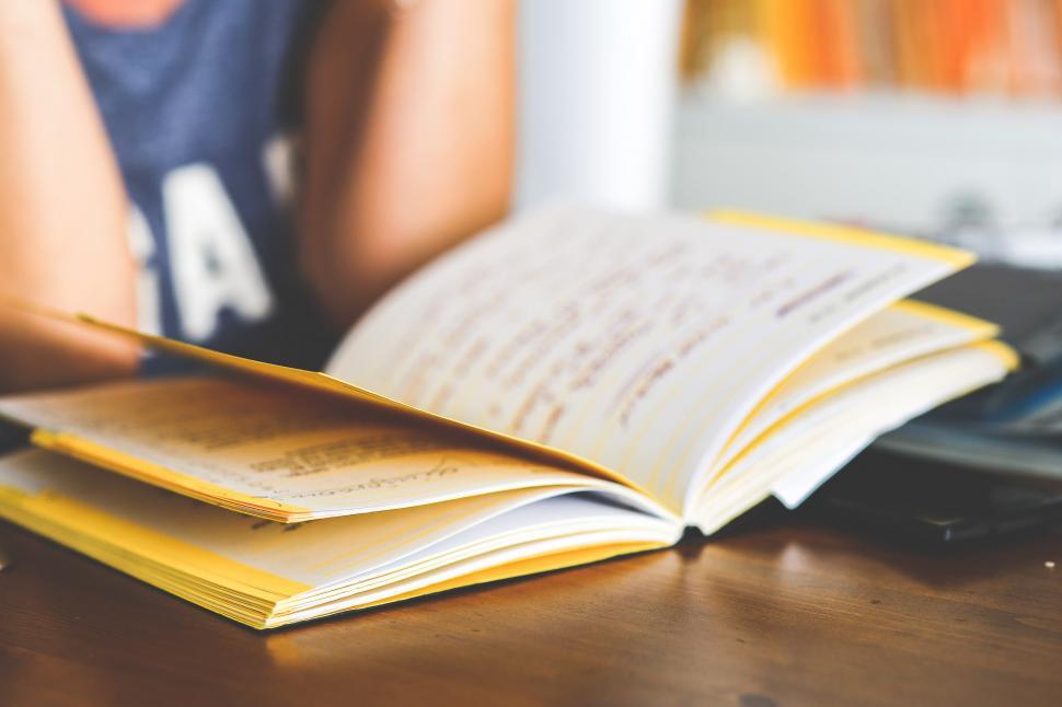 Free Image of Person Sitting at Table With Book and Laptop 