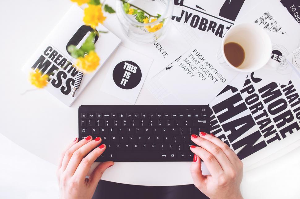 Free Image of Person Typing on Keyboard Beside Coffee Cup 