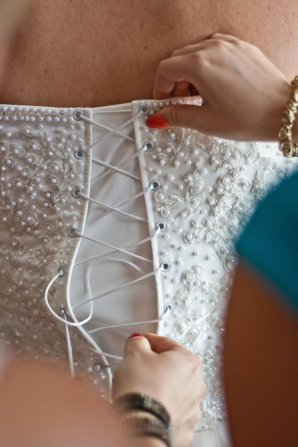 Free Image of Woman in White Dress Working on Dress 