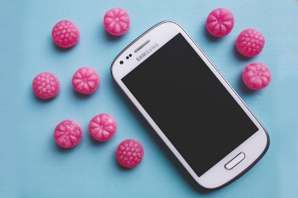 Free Image of Cell Phone Surrounded by Raspberries on Blue Surface 
