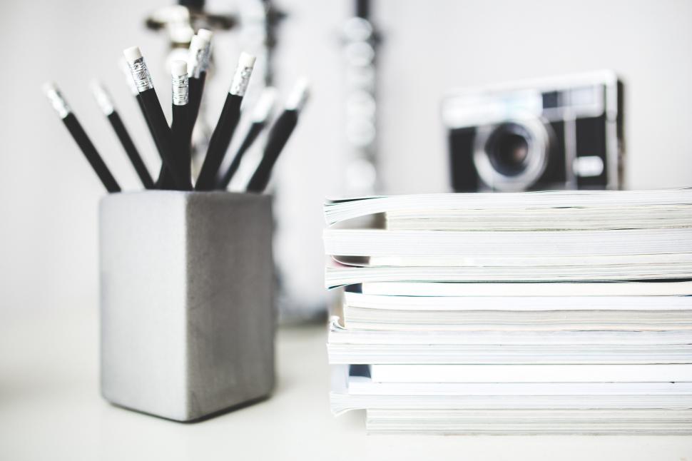Free Image of Desk With Stack of Papers and Camera 